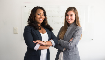 A picture of two businesswomen standing in their office space preparing for leadership training